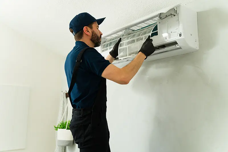 Man in blue repairing min-split AC unit